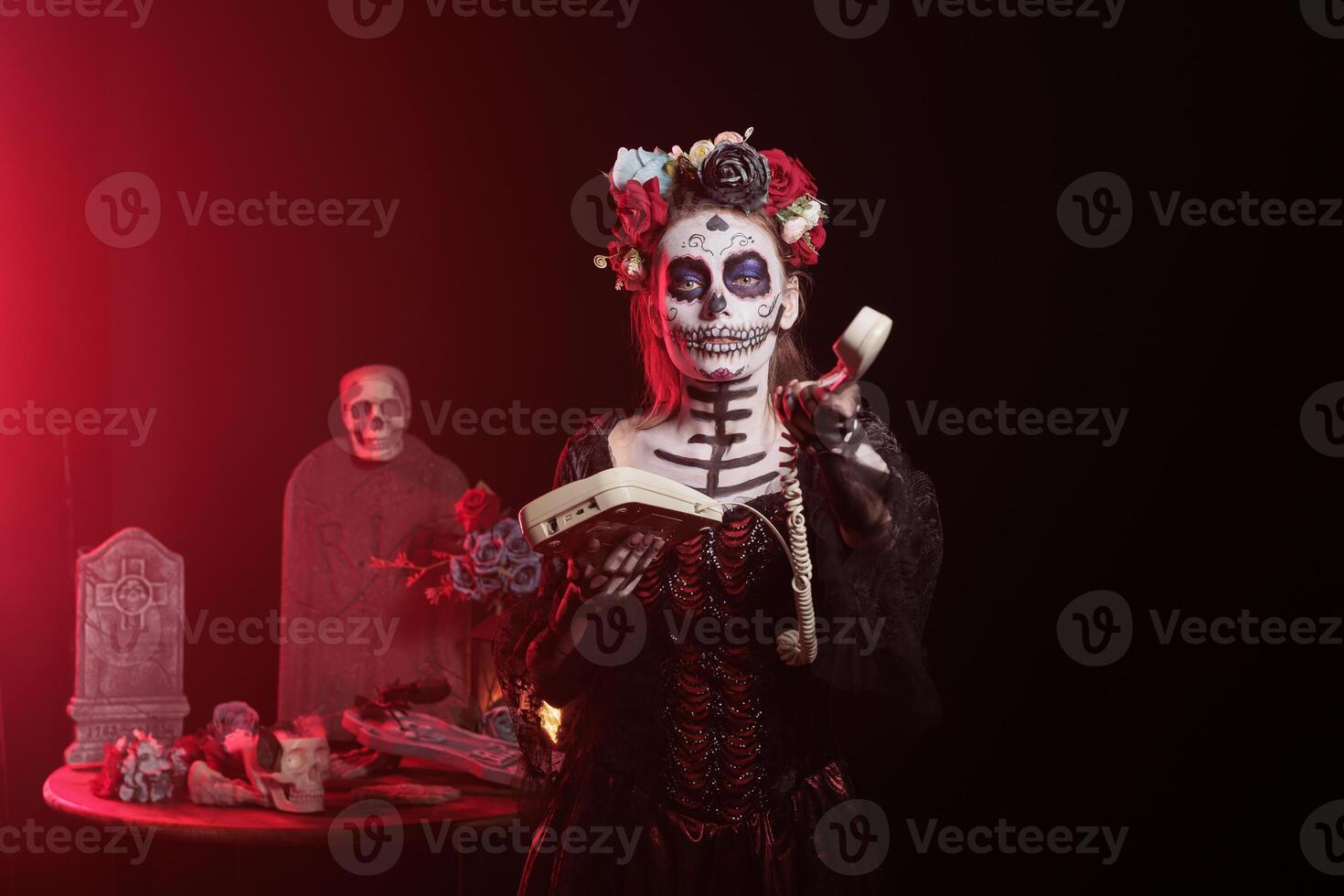 Woman talking on office cord telephone at Day of the Dead event to remember the deceased. Lady using landline phone to answer call during Mexican holiday of remembrance for those who have passed photo