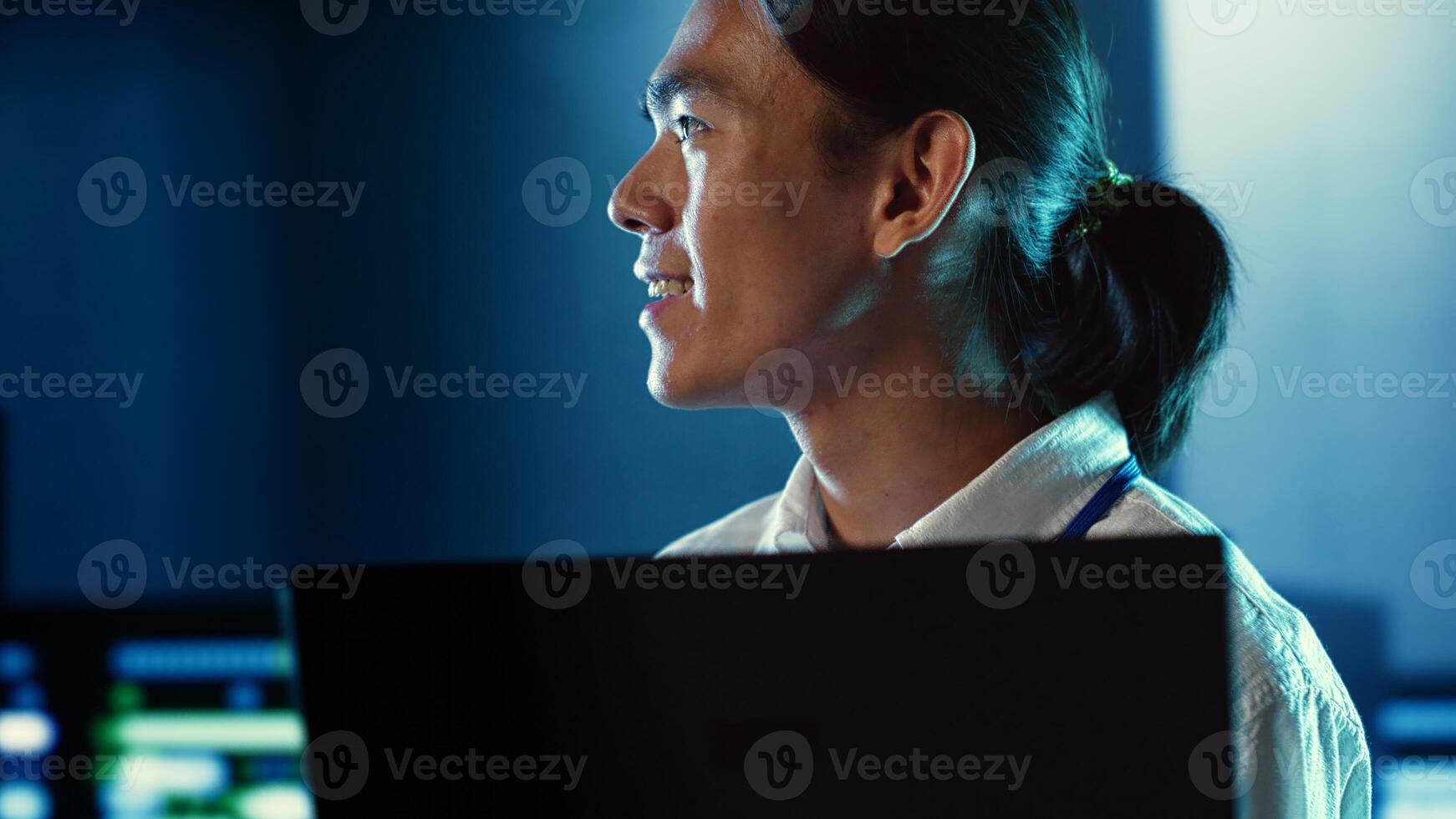 Close up shot of happy employee wandering around data center infrastructure providing processing resources for different workloads. Smiling admin doing analysis on servers photo