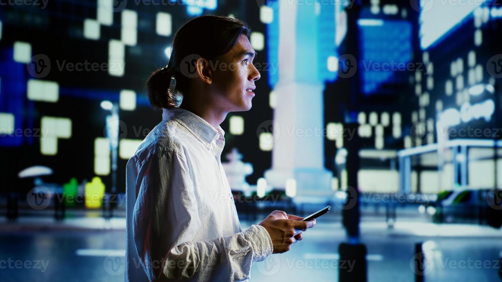 Man walking around city at night, scrolling on online shopping platform using mobile phone, blurry cityscape background. Person using smartphone while strolling on empty streets illuminated by lamps photo