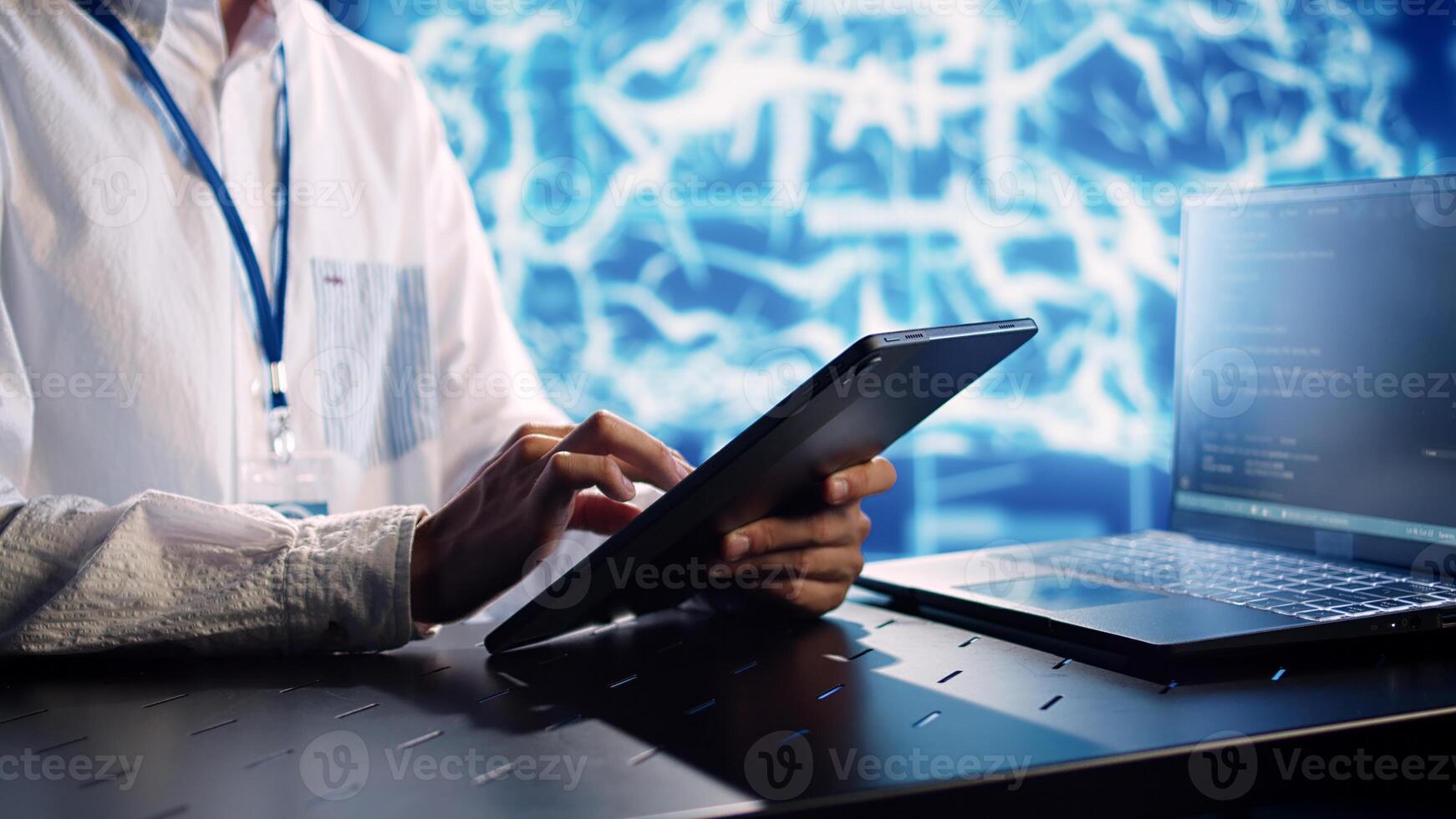 System administrator in data center, solving tasks on tablet while running programming scripts on laptop terminal. Experienced programmer manipulating lines of code for AI applications development photo