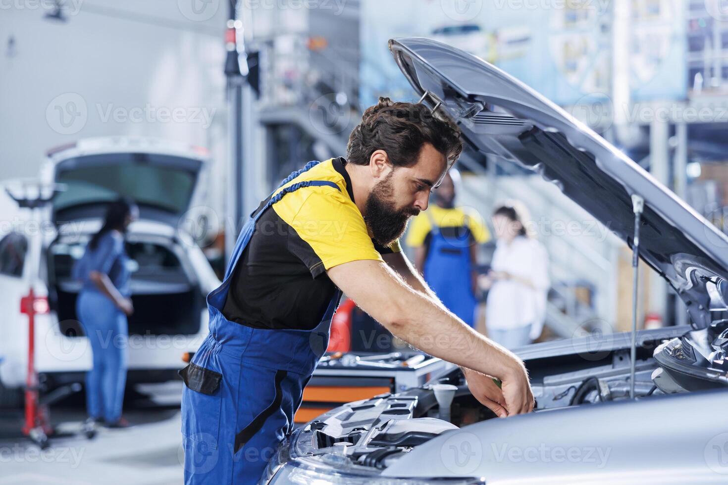 Car service technician expertly examines engine using advanced mechanical tools, ensuring smooth automotive performance and safety. Competent garage expert conducts routine vehicle checkup photo