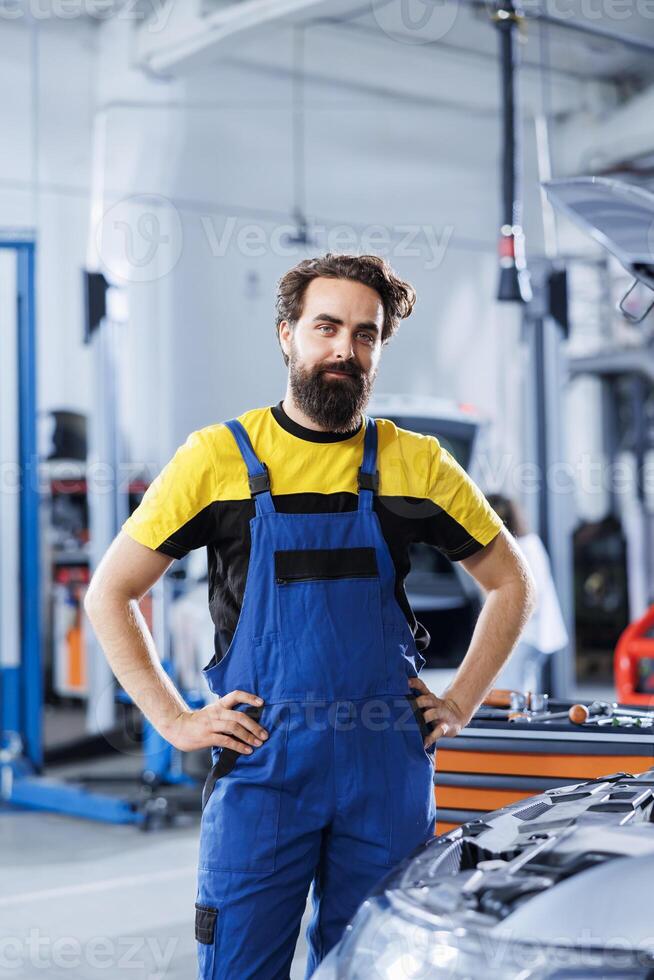Portrait of proud serviceman in auto repair shop tasked with fixing broken cars. Knowledgeable specialist in garage ready to start doing checkups on automobiles in garage workspace photo