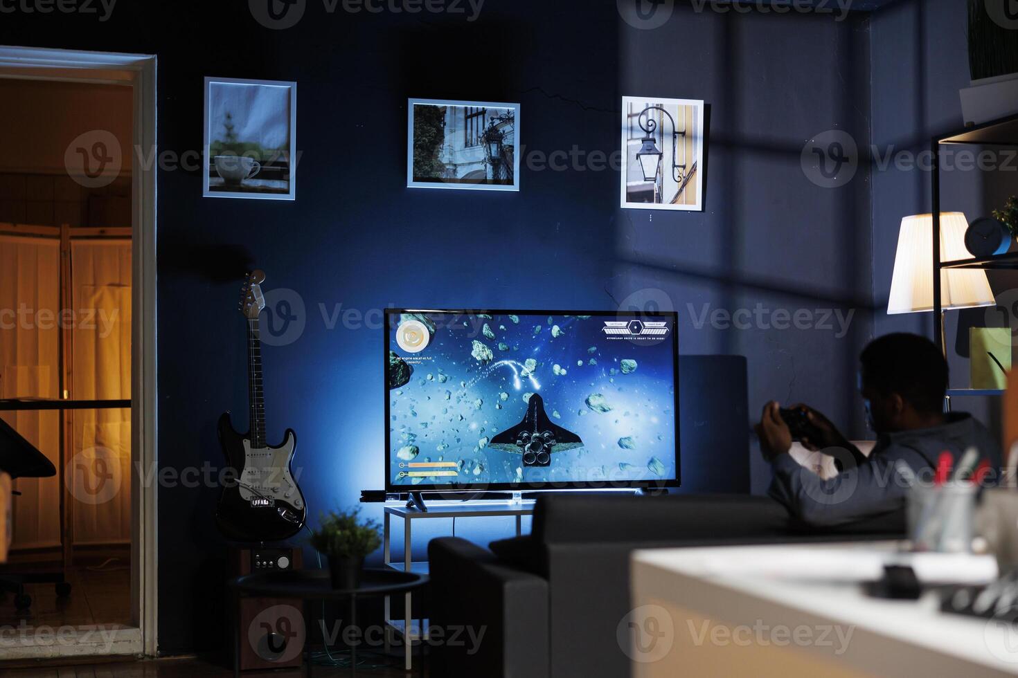 Online gamer enjoying shooter gaming competition at home, participating in multiplayer shooting tournament with friends at night. Young player having fun with games championship. photo