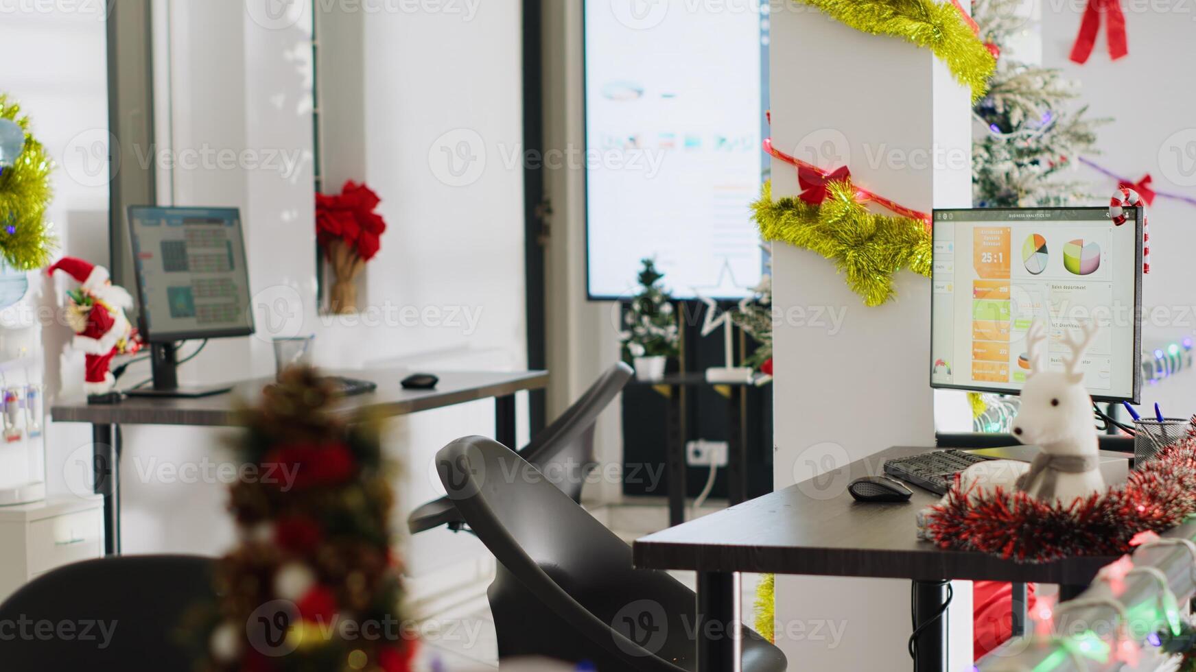 Empty festive ornate office properly decorated for company Christmas festivities. Accounting figures on computer screens in xmas adorn workplace with no workers during winter holiday season photo