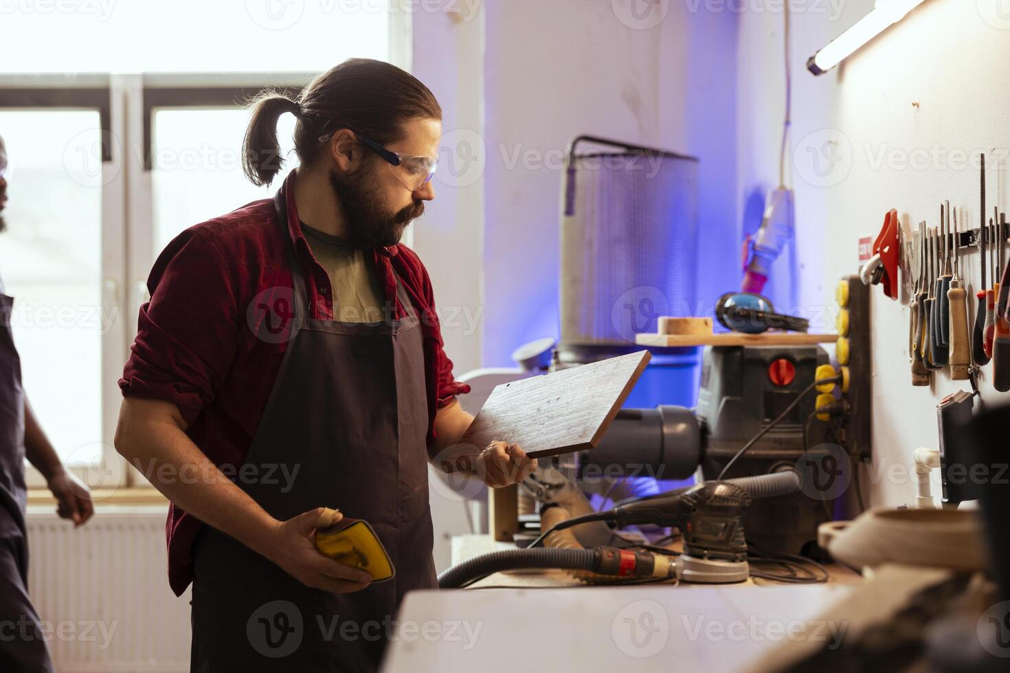Carpenter doing last touches on piece of wood before using it for furniture assembly, sanding it with sandpaper. Woodworking expert doing woodworking process on lumber block, inspecting for damages photo