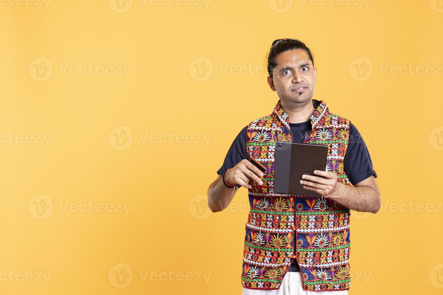 Portrait of irked indian man upset after lacking necessary money while trying to buy stuff online on tablet. Annoyed person frustrated after getting transaction rejected on digital device photo