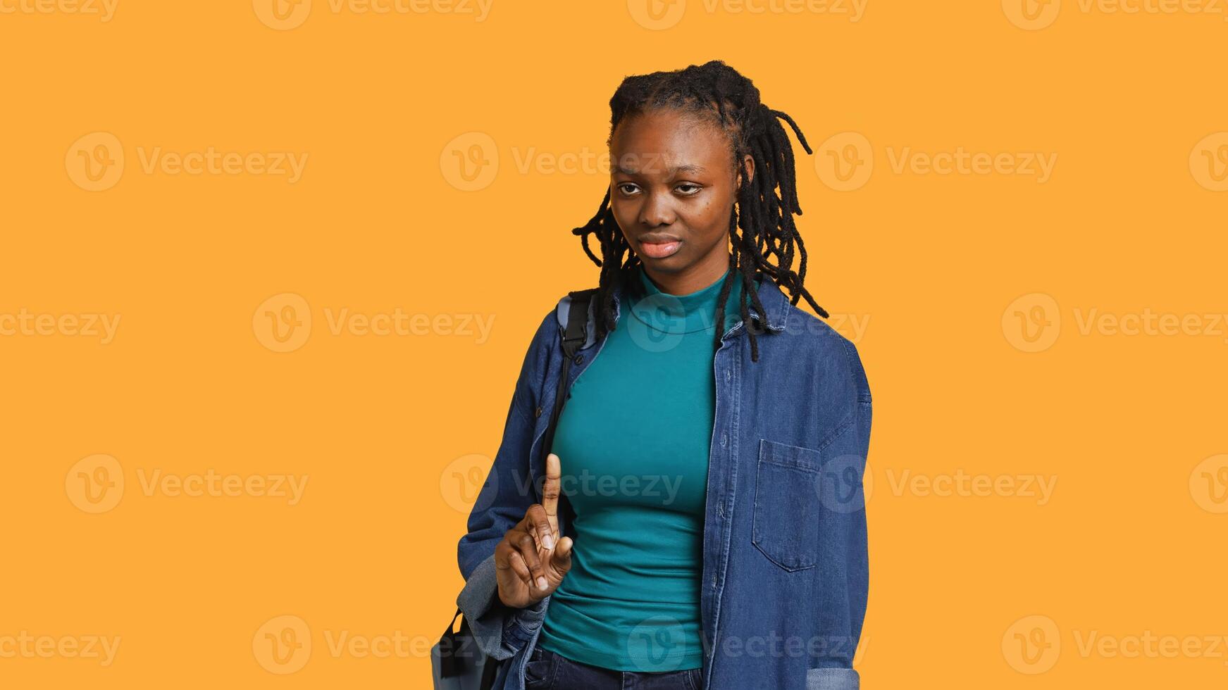Anxious student at school thinking of raising arm to answer question but unsure of herself, studio background. Teenager lacking confidence needed to volunteer saying explanation to question, camera A photo