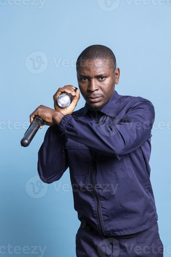 Trained bodyguard inspecting the perimeter with flashlight and weapon, going on a patrol at night in the dark for safety control. Security agent looking around with his lantern. photo