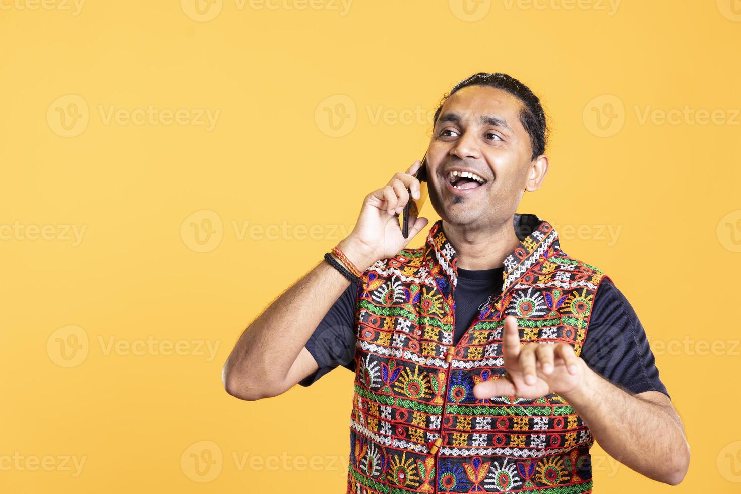 Cheerful man laughing at funny jokes with best friend over telephone call using smartphone. Person talking with hilarious mate in phone call using mobile phone, having fun, studio background photo