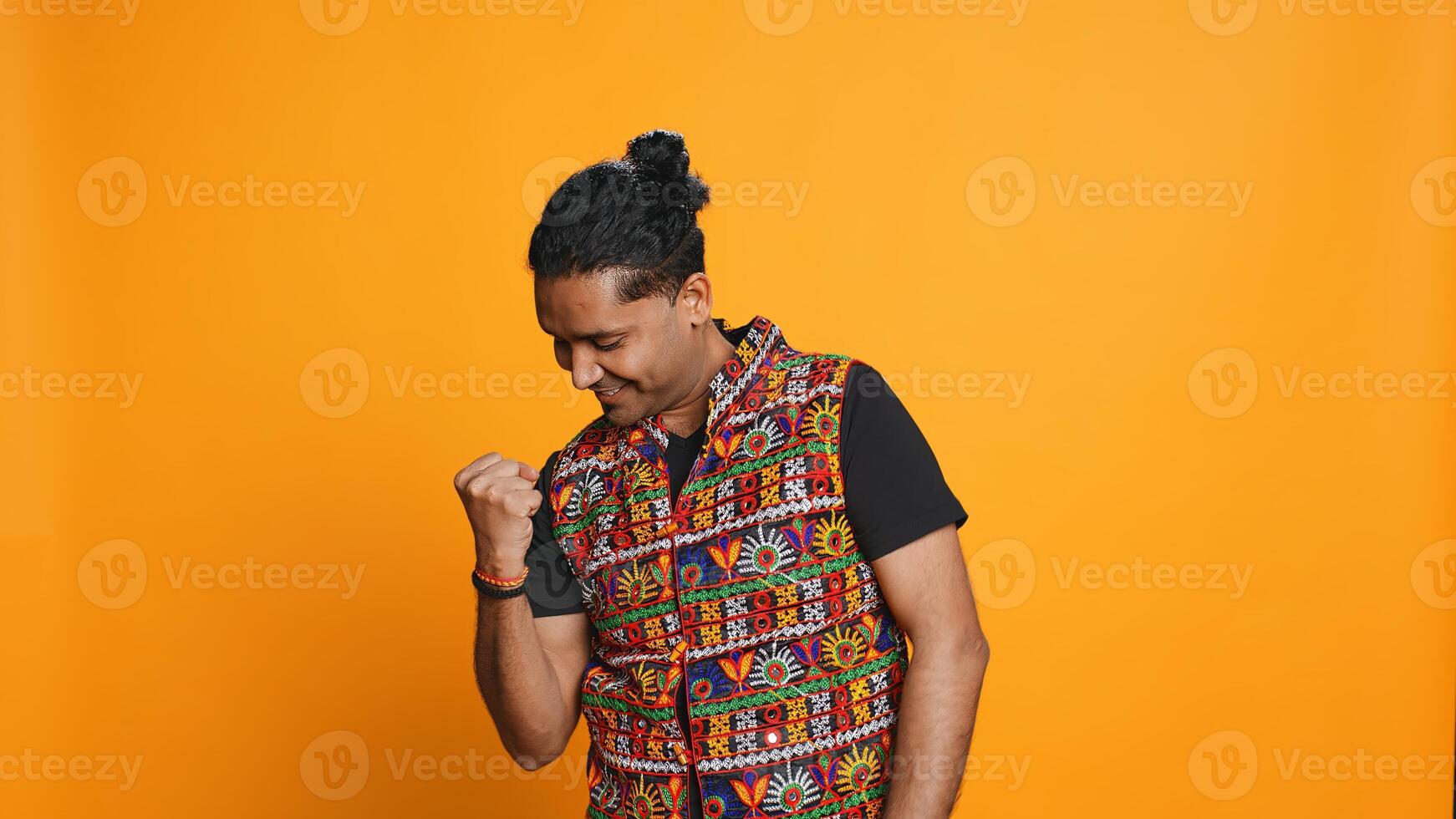 Portrait of joyful indian man celebrating, showing positive emotions, feeling happy. Delighted person thrilled by achievement, cheering and gesticulating, studio background, camera B photo