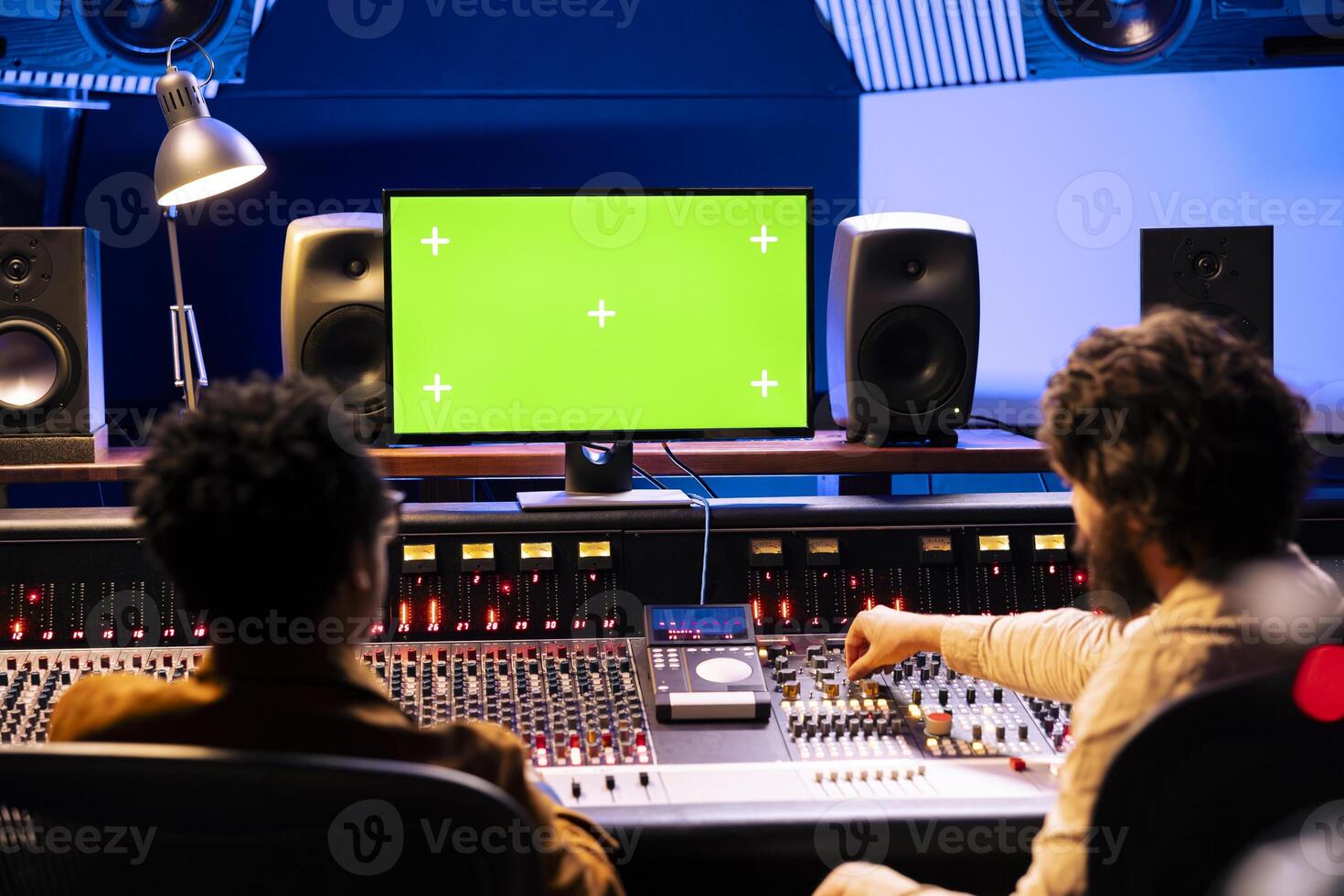Team of specialists recording and editing tracks with isolated screen on pc, working on a new album and creating songs. Audio engineer operating mixing console with motorized faders. photo