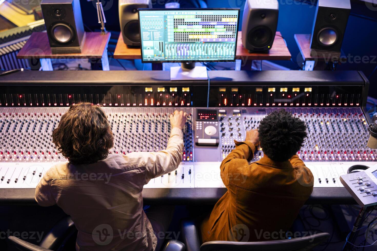 Audio expert and singer collaborating on music for new album, composing and editing tracks with mixing console and digital software on pc. Artist working with producer for cool records in studio. photo