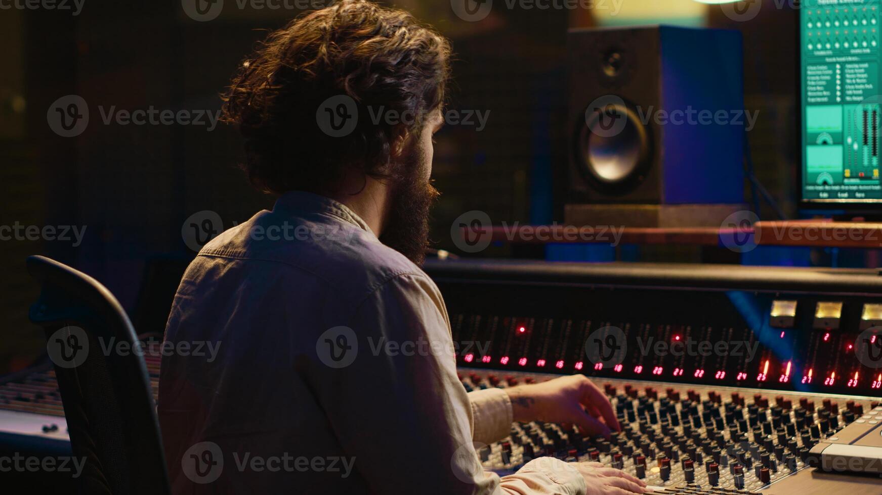 Mixing engineer focuses on blending and balancing individual tunes of a recording to create song, audio editing software in control room. Expert deals with technical aspects of sound. Camera A. photo