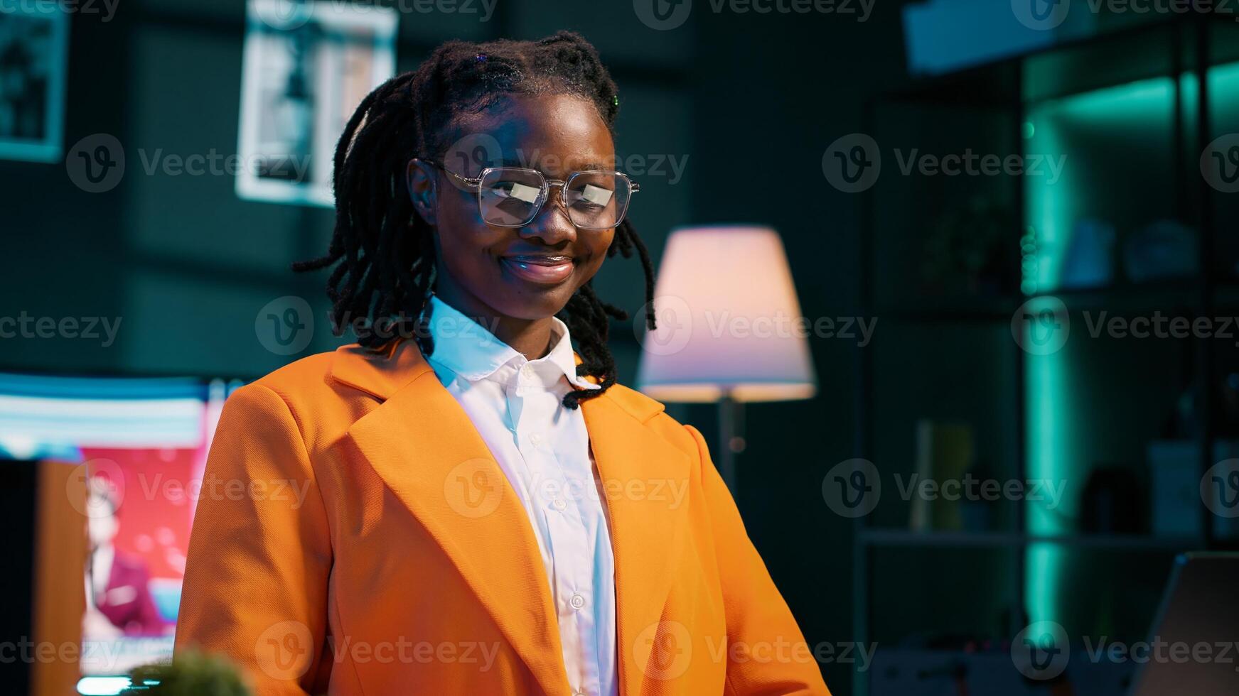 Portrait of african american student putting glasses on and working on english essays at home, reading academic databases for additional resources. Young woman studying at university. Camera A. photo