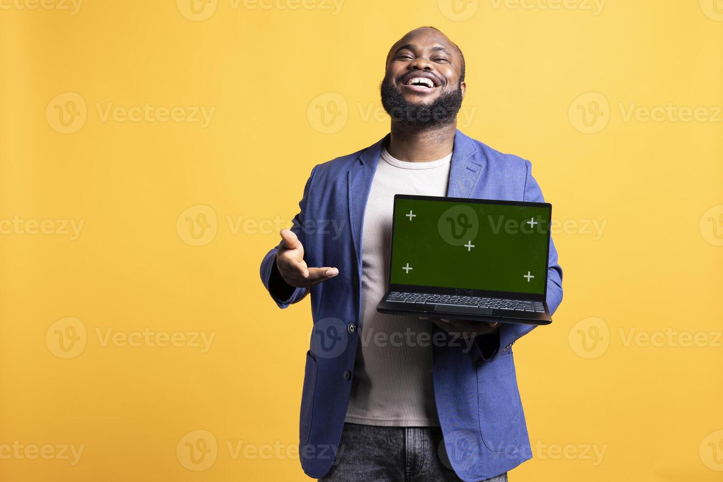 Portrait of relaxed carefree man pointing towards green screen laptop, doing endorsement. Delighted tech reviewer giving positive feedback to chroma key notebook, isolated over studio background photo