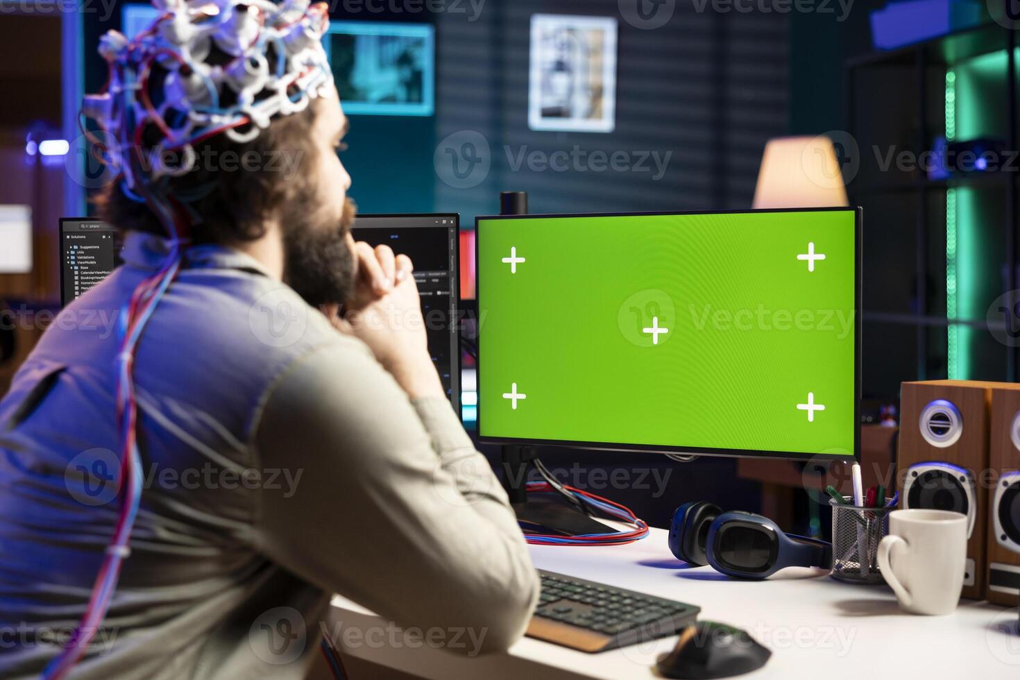 Neuroscientist using EEG headset to upload his mind into green screen computer, attaining immortality. Software developer using mockup PC, experimenting with transferring consciousness into cyberspace photo
