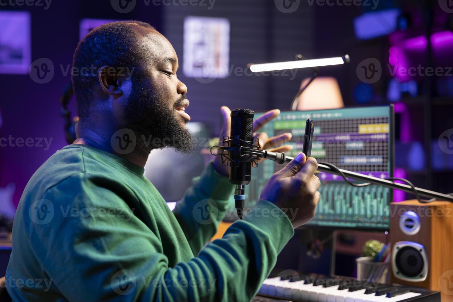 Famous musician singer performing an acoustic version of his track, reading the verses on his mobile phone. Skilled artist songwriter composing a new song, recording audio on microphone. photo