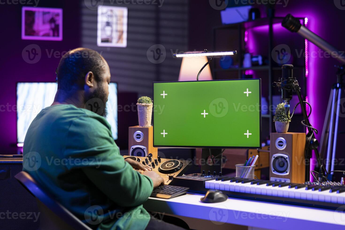 Young sound technician mixing music on console and piano with a greenscreen on pc display, home studio tools. Male composer producing soundtracks for a new album, stereo gear. photo
