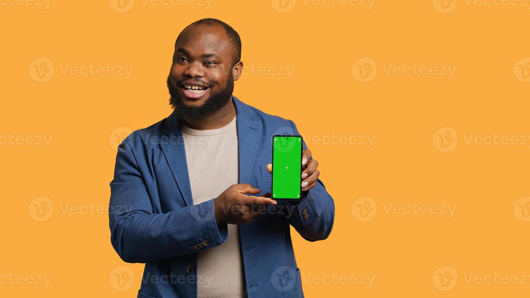 Smiling influencer presenting green screen mobile phone, isolated over studio background. Joyful BIPOC person holding copy space chroma key smartphone used for advertising brands, camera A photo