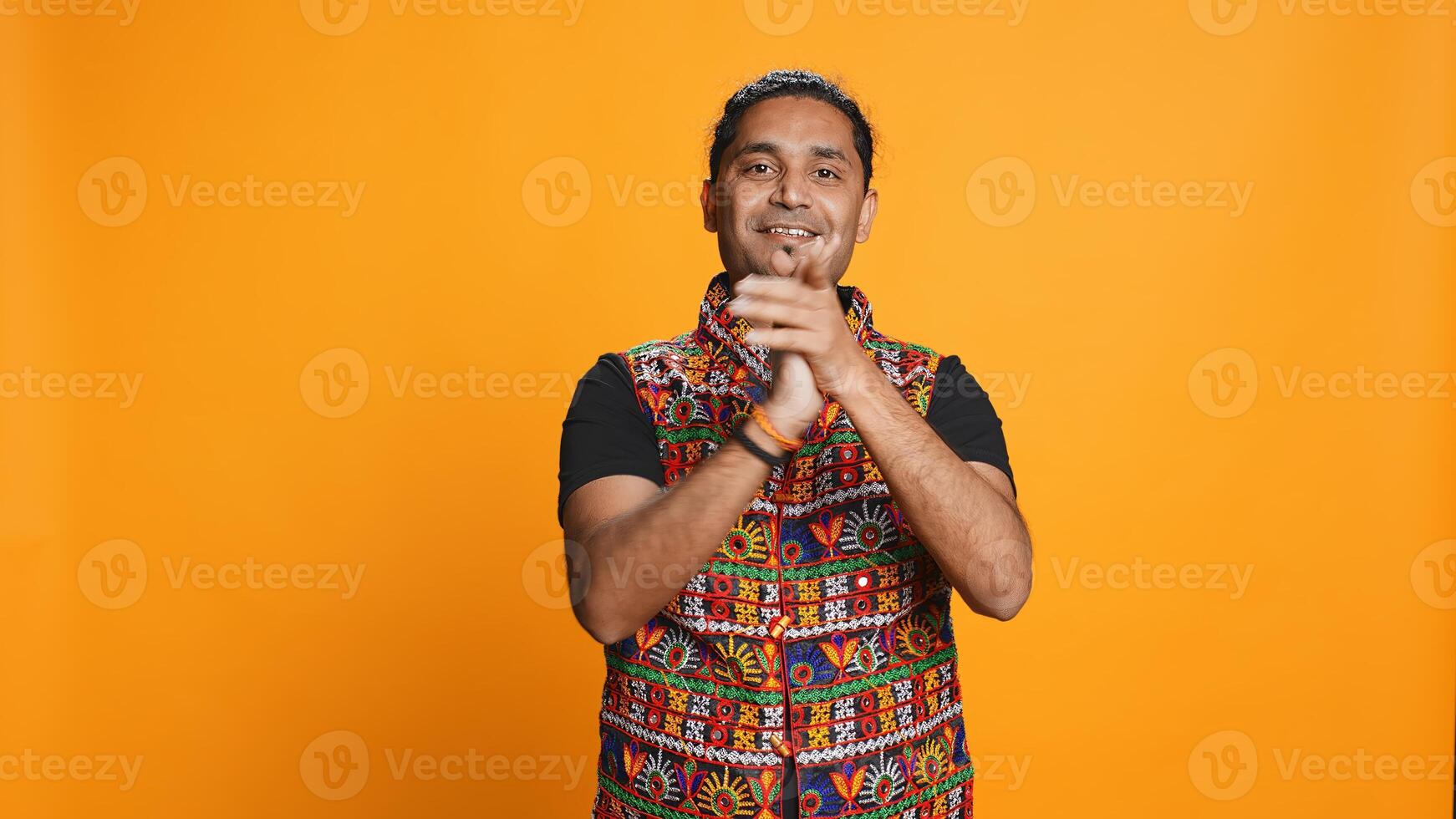 Joyful indian man happily clapping hands, ecstatic about accomplishments. Excited person reacting to good news, cheering, applauding, isolated over studio background, camera B photo