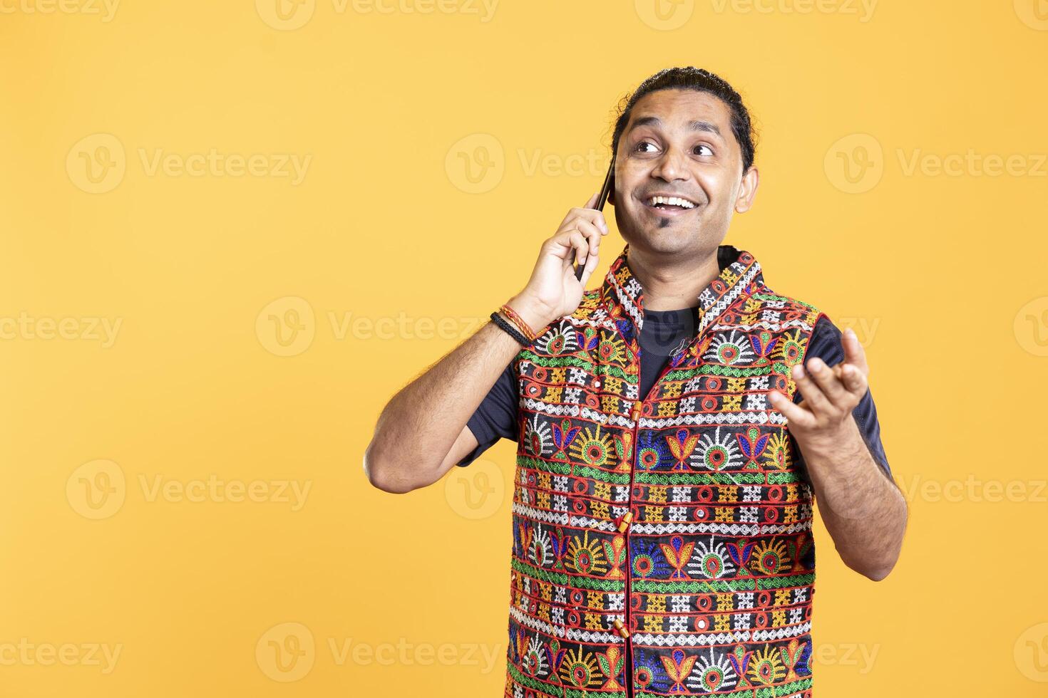 Joyful man happy to hear from best friend over telephone call using smartphone. Cheerful person talking with mate in phone call using mobile phone, being entertained, studio background photo