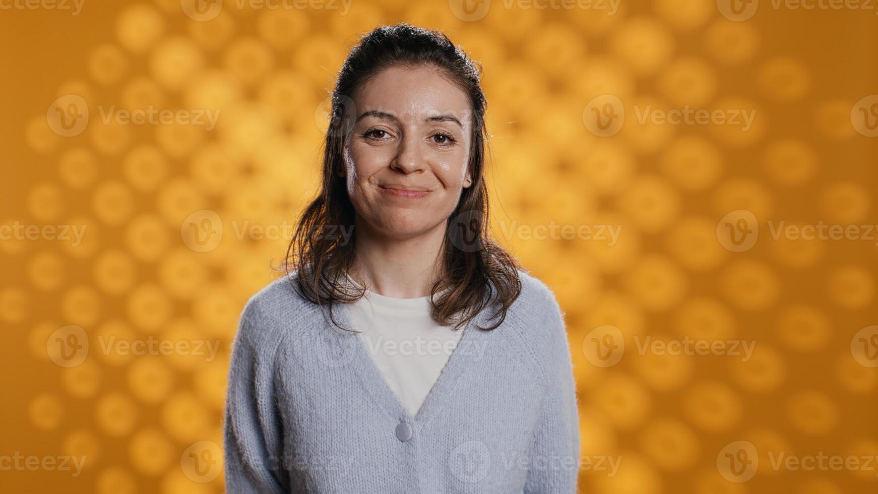 Portrait of upbeat optimistic woman posing, feeling happy and relaxed, isolated over yellow studio background. Close up shot of lively radiant caucasian lady standing, camera B photo