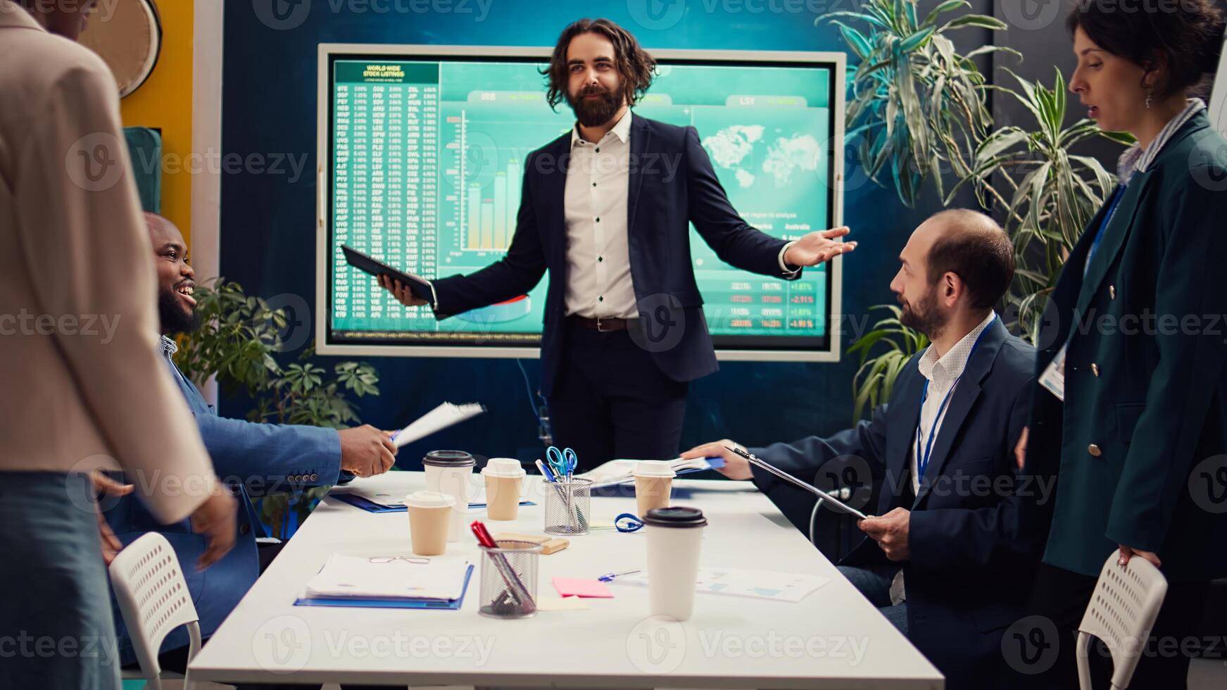 Chief executive officer greeting his employees in a boardroom, starting action review meeting. Manager helps staff members to develop confidence, gain insight and improve themselves. Camera B. photo