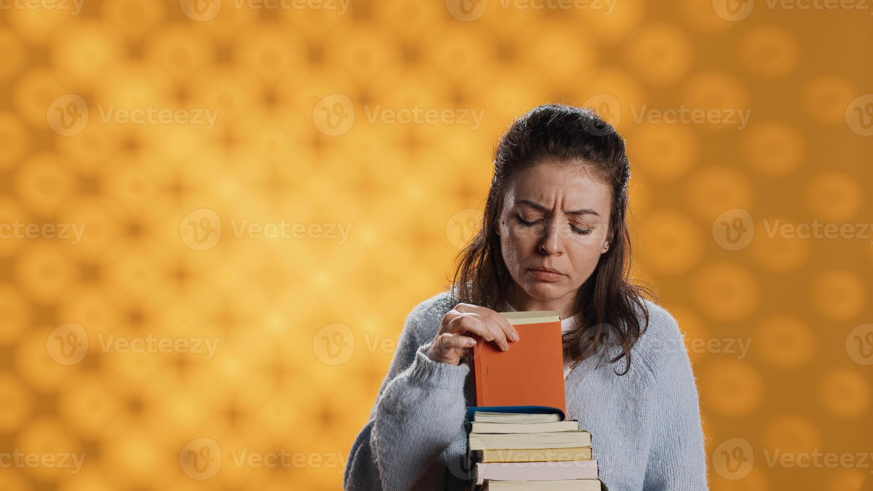 Portrait of woman browsing through stack of textbooks, gathering information for school exam, isolated over studio background. Person searching necessary course for exam in pile of books, camera A photo
