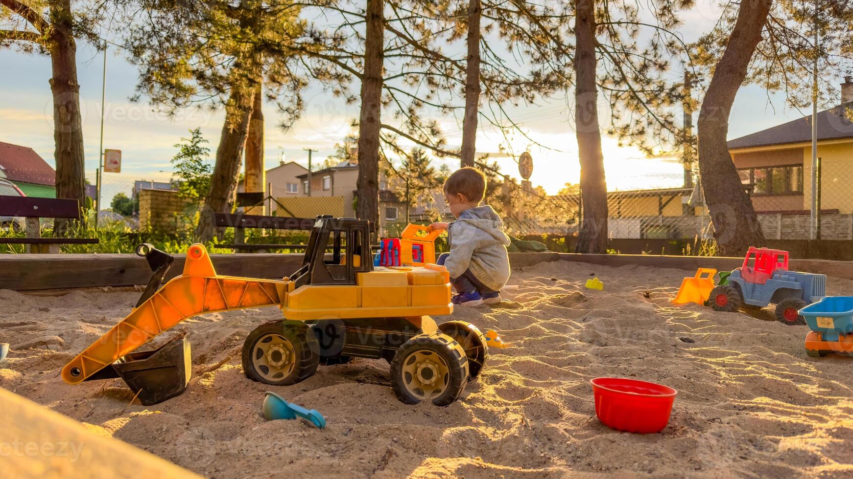 Child playing with toys in sandbox. Boy having fun on playground in sandpit photo