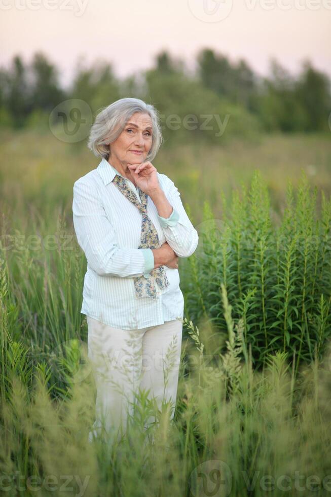 Portrait of happy senior woman posing in spring park photo