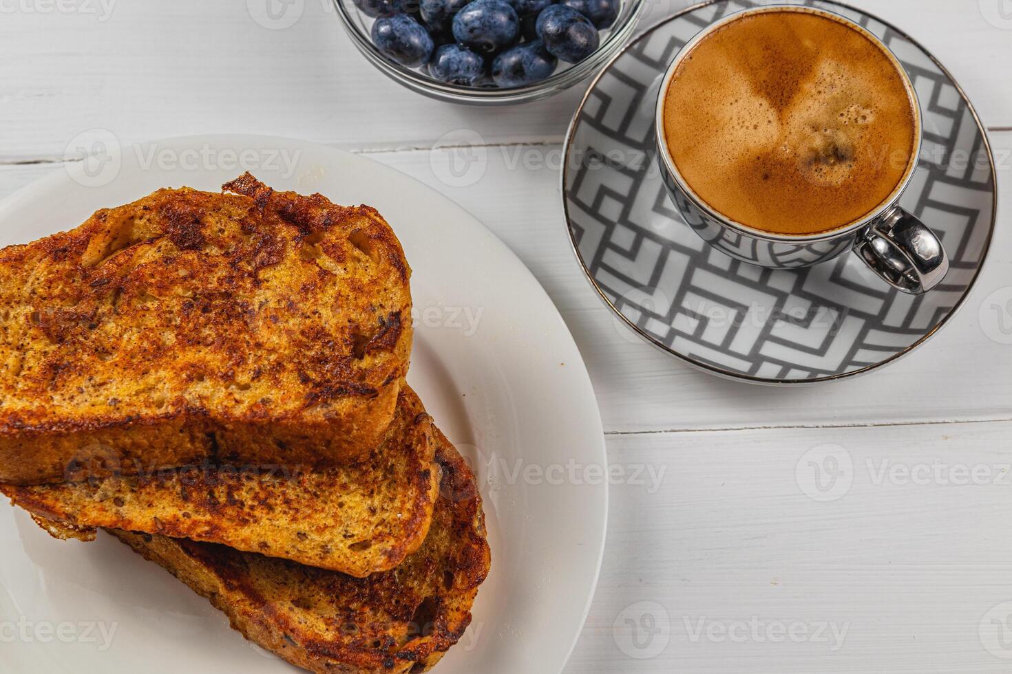 French toast on a white plate with blueberries and coffee for breakfast photo