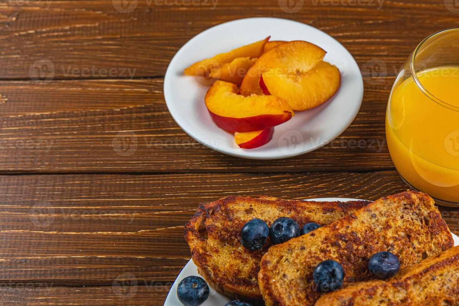 French toast on a plate with blueberries, orange juice, nectarine for breakfast photo