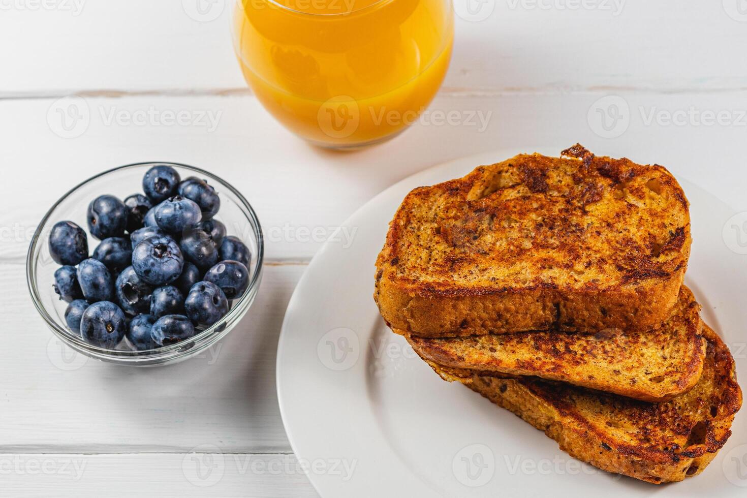 French toast on a white plate with blueberries and orange juice for breakfast photo