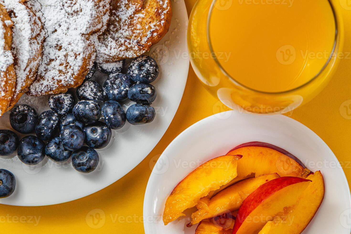 French toast on a plate with blueberries, orange juice, nectarine for breakfast photo