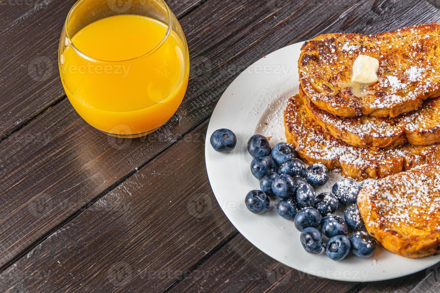 French toast on a white plate with blueberries and orange juice for breakfast photo