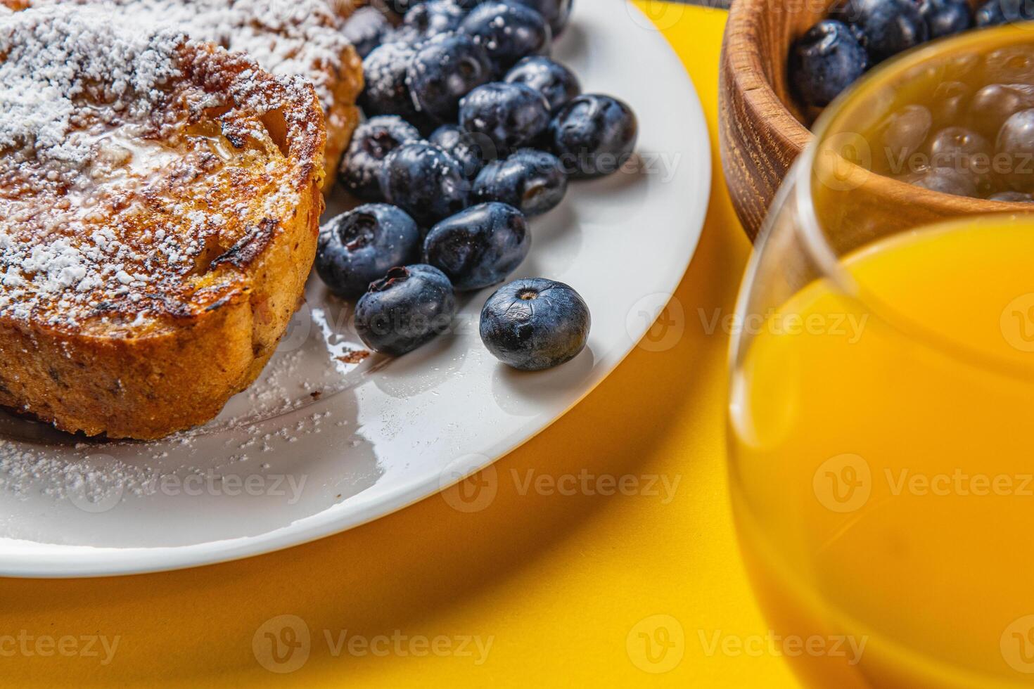 French toast on a white plate with blueberries and orange juice for breakfast photo