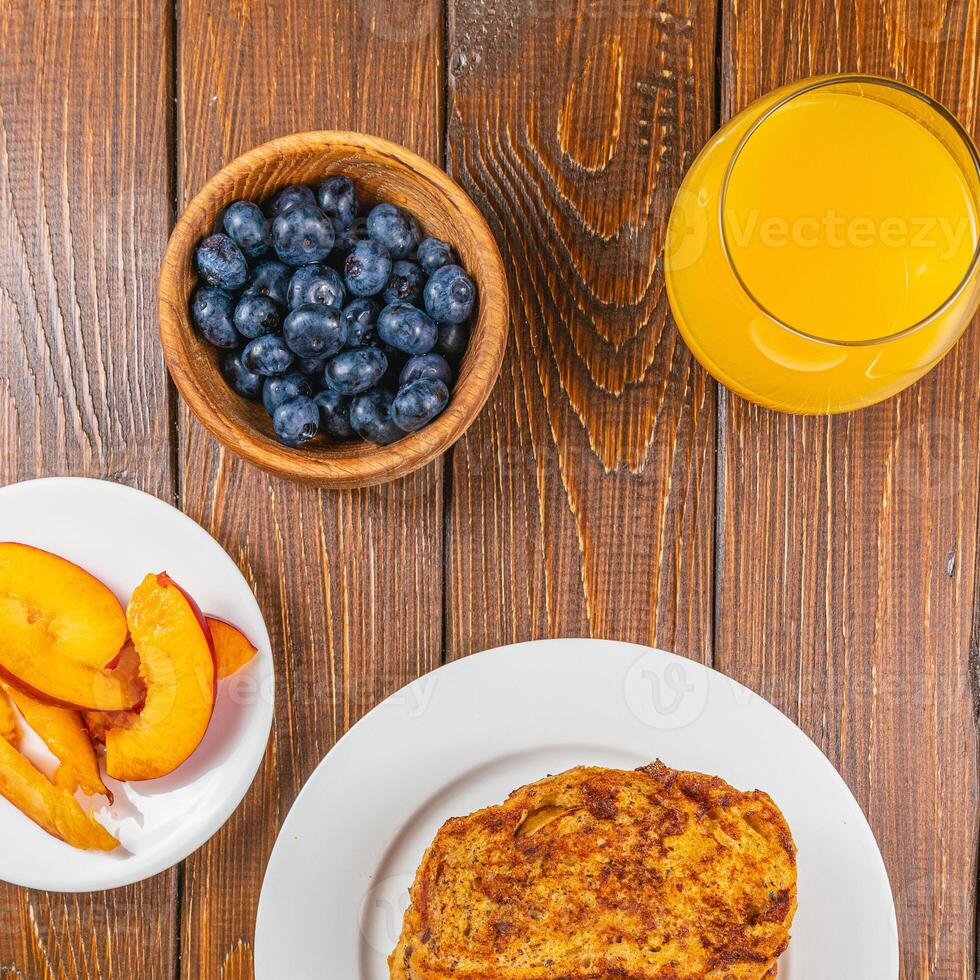 French toast on a plate with blueberries, orange juice, nectarine for breakfast photo