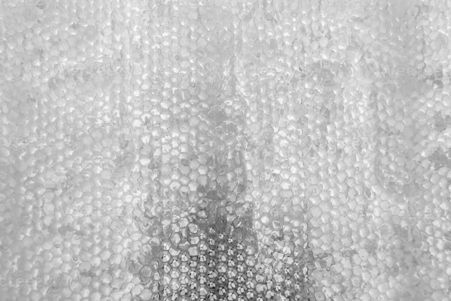 Drop of bee honey drip from hexagonal honeycombs filled with golden nectar photo