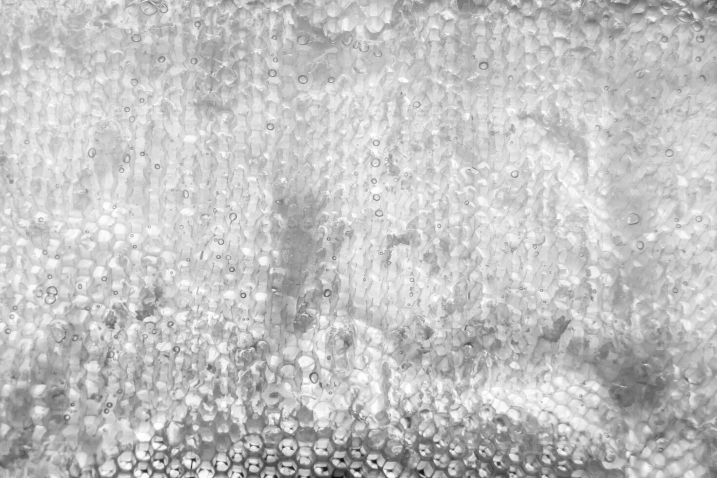 Drop of bee honey drip from hexagonal honeycombs filled with golden nectar photo