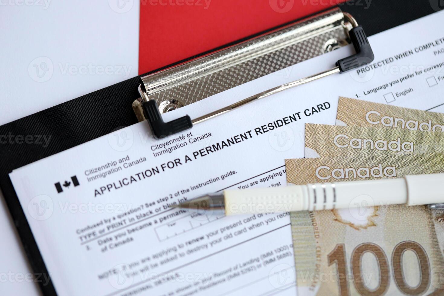 Application for permanent resident card on table with pen and canadian money photo