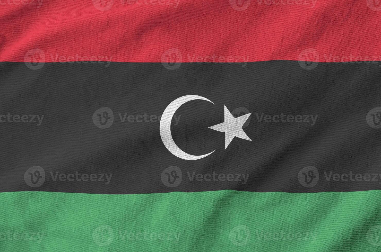 Libya flag depicted on folded wavy fabric of old cloth photo