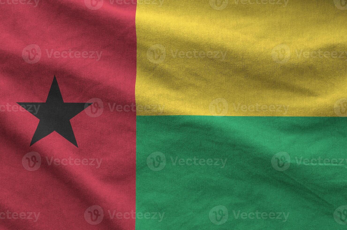 Guinea Bissau flag depicted on folded wavy fabric of old cloth photo