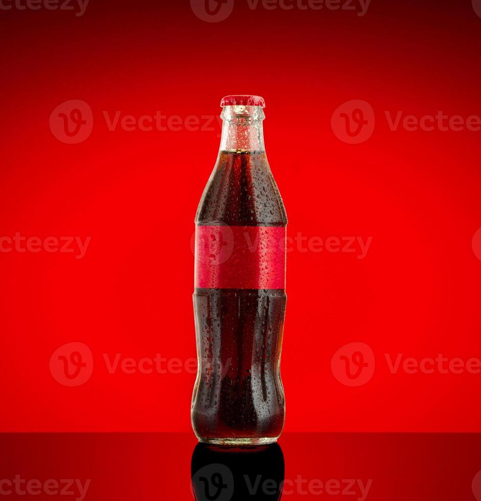 Cola soft drink in a glass bottle on red Background. photo