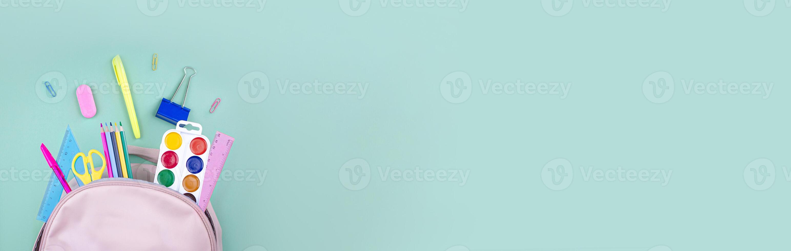 School backpack and school stationery on a mint green background top view. Concept back to school. Banner copy space photo