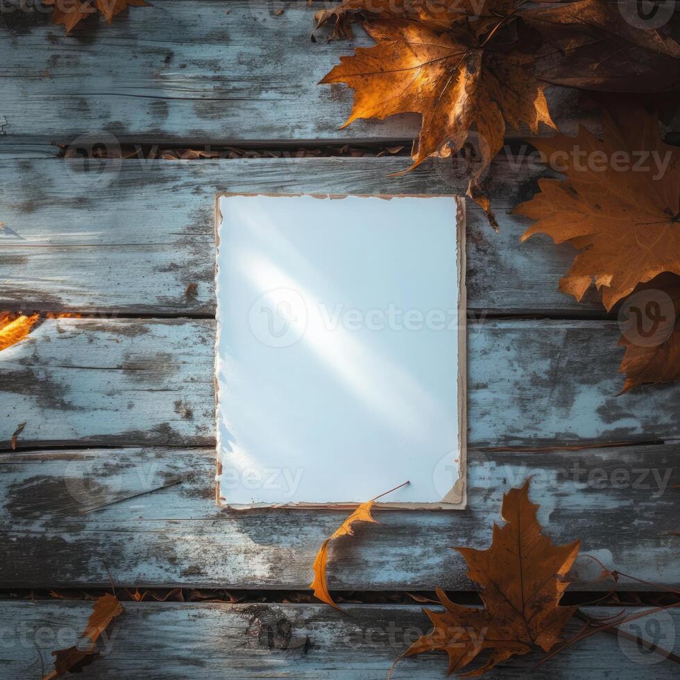 Blank notepad surrounded by autumn leaves on a rustic wooden table in late afternoon light photo