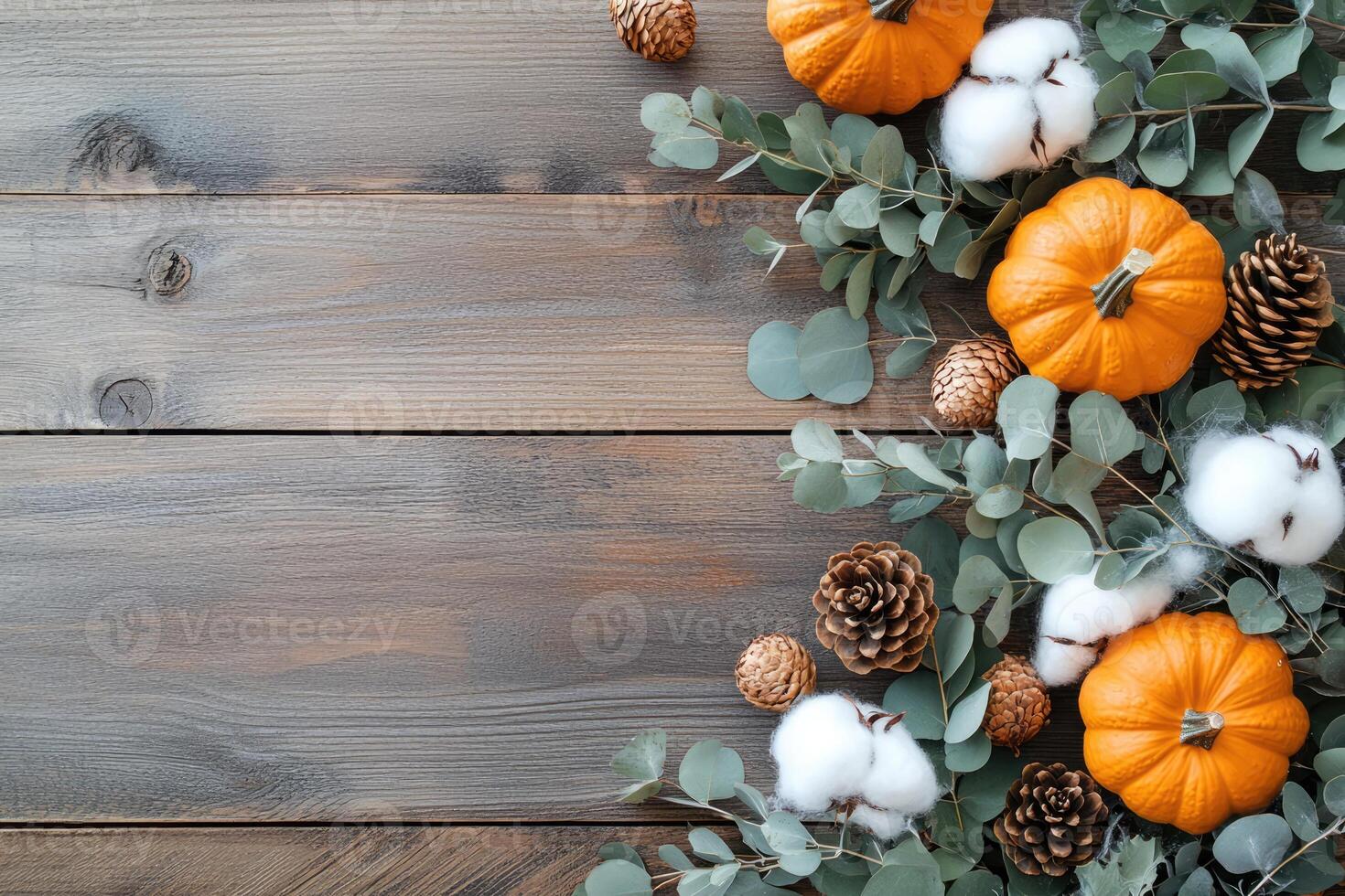 Autumn arrangement featuring pumpkins, eucalyptus, pine cones, and cotton bolls on rustic wooden background photo