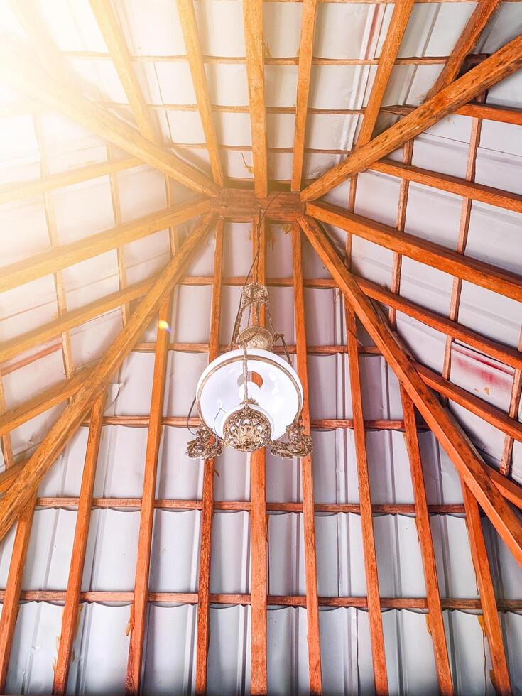 Joglo is the name of a traditional Javanese house. The interior of the Joglo roof is teak wood with antique glass lamps. hanging decorative lights in a Javanese-style hall photo