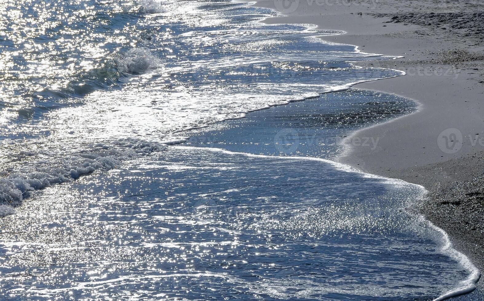 Bright reflections on the water on a sunny day on the sandy shore of the Black Sea photo