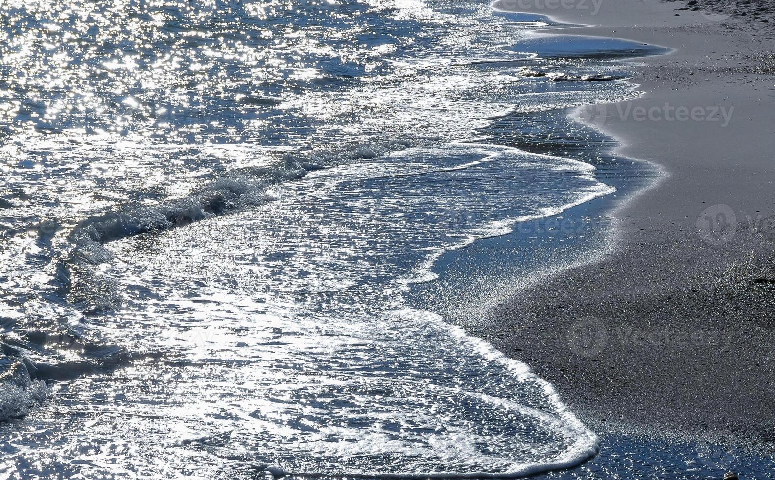 Bright reflections on the water on a sunny day on the sandy shore of the Black Sea photo