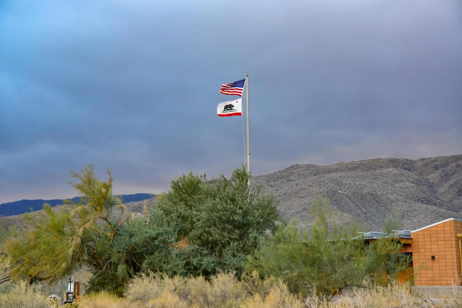 CALIFORNIA, USA - NOVEMBER 27, 2019 the flag of the USA and California on the background of the mountains photo